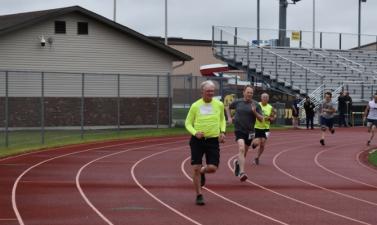 three men running in track event