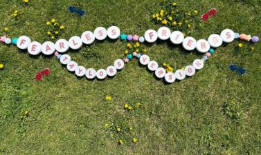 large friendship bracelet on grass that says "Fearless Friends Taylor's Version"