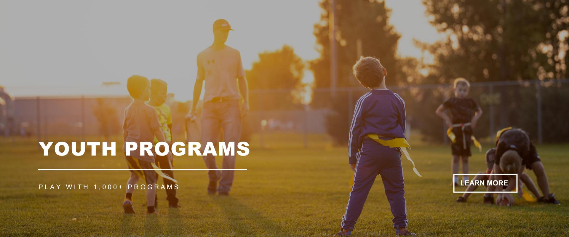 5 Young Boys & 1 Coach playing flag football as the sun goes down,  YOUTH PROGRAMS - Play with 1,000+ Programs - Learn More button