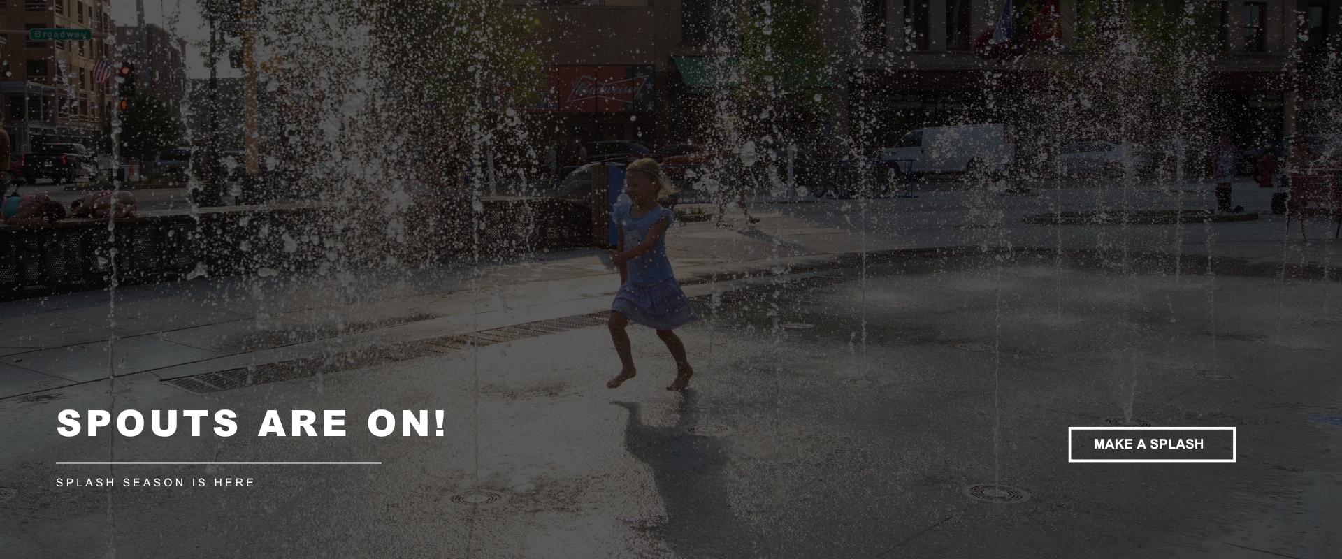 Young child runs through water fountains at an outdoor splash pad in downtown Fargo. Text reads “Spouts Are On!” and “Splash season is here!.”