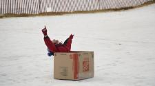 This image shows a boy sledding down Mickleson Sledding Hill for Cardboard Sled Race. 