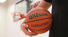 This image shows someone holding a basketball with the hoop in the background.