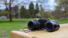 Photo shows binoculars on picnic table.