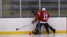 This image shows two players along the boards during broomball.