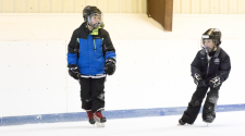 This image shows two boys skating at Open Hockey.