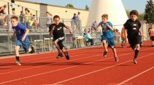This image shows four boys racing at the track and field program.