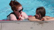 Photo shows lifeguard talking to girl in pool at Water Safety Day.