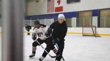 This image shows men skating on the ice at Drop In Hockey.