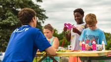 This image shows three kids working with an instructor at a craft table during Monstrous Imagination.