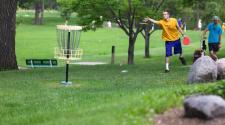 This image shows a male throwing his frisbee into the disc golf basket.