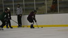 This image shows a female getting the puck along the boards at adult hockey.