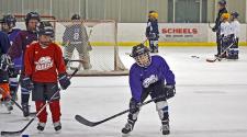 This image shows a group of players getting ready to start a drill at youth hockey skills training.