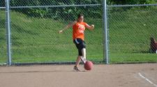 This image shows a female kicking the ball during kickball league.