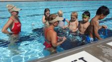 This image shows two femaile lifeguards teaching kids to swim.