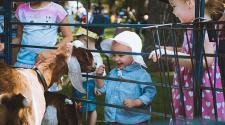 This image shows two girls looking at the goats at Midwest Kids Fest.