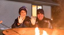 This image shows an adult and child warming up by a firepit at S'mores and More.