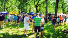 Photo shows tents and people in park.