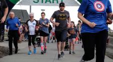 Photo shows runners leaving the starting line of 5k run.