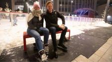 This image shows a male and female posing for the camera while putting on their ice skates at Broadway Square.