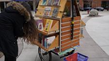 This image shows a person looking at the titles available on the book bike cart.