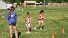 two kids at the starting line for race event in grass field for kids triathlon with Staff member calling go