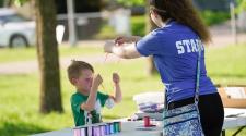 Kid making a medal for his award at craft table with staff member assisting