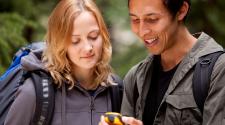 A woman and man looking at a GPD device in backpacks in park