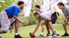 5 men on the line of scrimmage - 3 on offense, 2 on defense outside in a park playing flag football