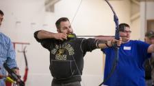 two men shooting a bow and arrow inside a building