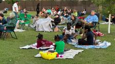 20+ people sit on the lawn in folding chairs or on blankets waiting for the Movie in the Park movie to start at Rheault Farm