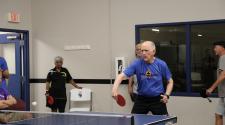 This image shows senior athletes playing table tennis indoors during the North Dakota Senior Games.