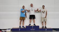 Three male athletes stand on a podium with medals for first, second, and third place at the North Dakota Senior Games.