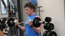 This image shows a woman lifting a barbell while strength training during the North Dakota Senior Games.