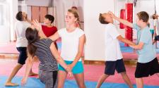 Youth practice self-defense techniques with partners during a hands-on class.