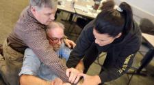 An instructor guides participants through a hands-on self-defense technique during a class.
